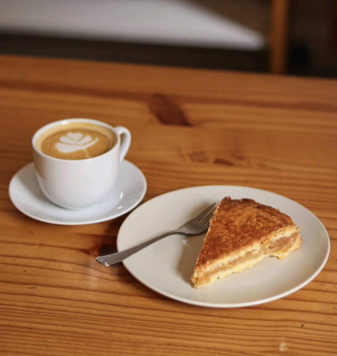 Flat white and a slice of Dutch almond tart on a wooden table