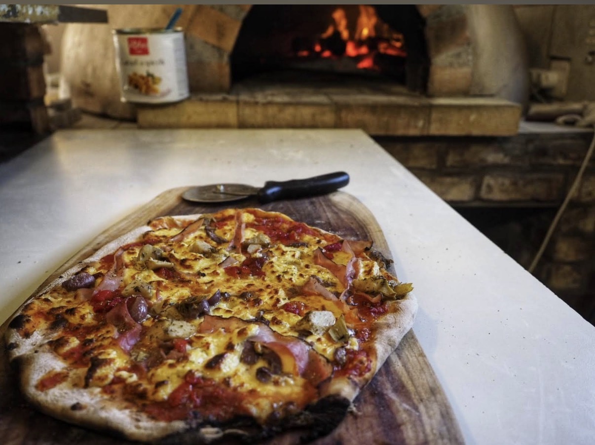 Wood-fired pizza in front of a glowing oven at Mac Butners